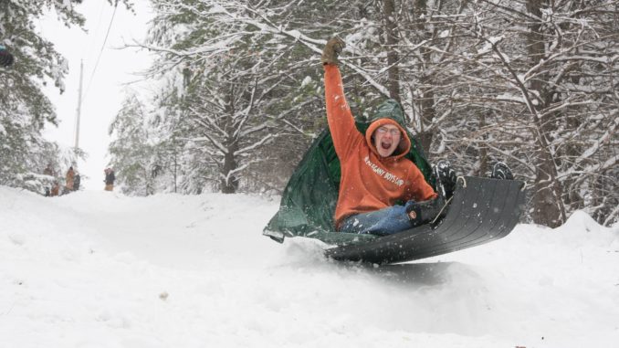 snow 2018 (2) downsized boy raising fist as he sleds over snow ramp